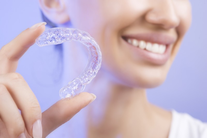 Adult patient holding a clear aligner tray at Brighten Dental Care in Dania Beach, FL